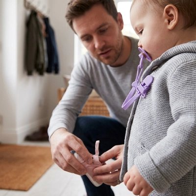 Attache tetine papa qui prépare bébé pour une sortie