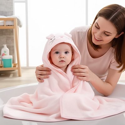 Cape de bain bébé  maman qui est essuie bébé dans une belle cape rose