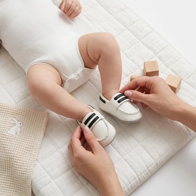 Chaussure bebe maman qui attache chaussure  a bébé