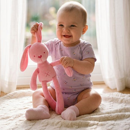 Doudou lapin bébé sourit tout en prennant plaisir a jouer au sol avec sa doudou lapin